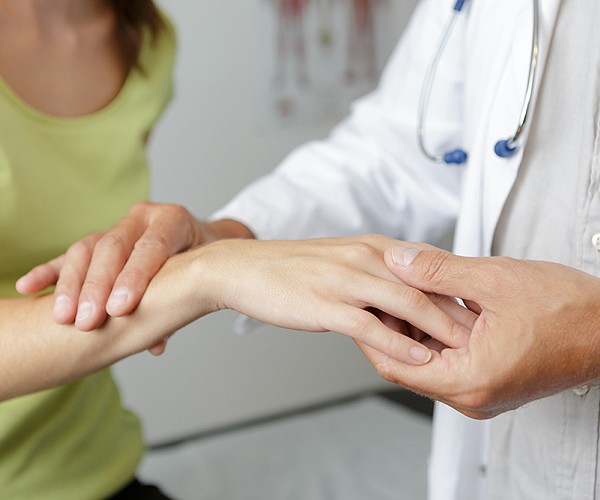 A doctor checking the hands and wrist of a patient