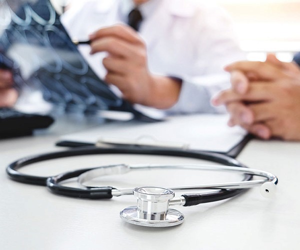 close up of a stethoscope on a table and a person inspecting a Xray